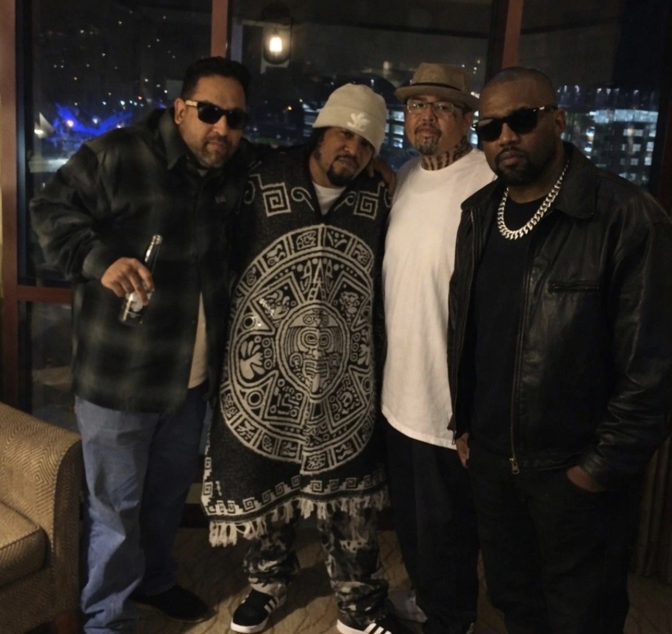 Frank “Nitty” Gibson Jr. with three others in a room overlooking a city at night